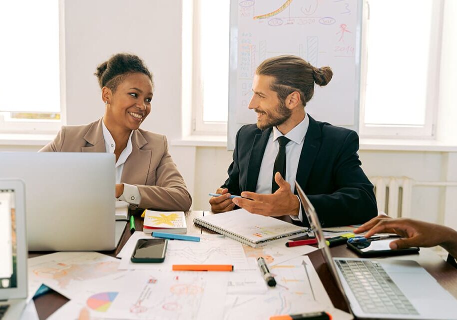 Two colleagues discussing work at a desk.